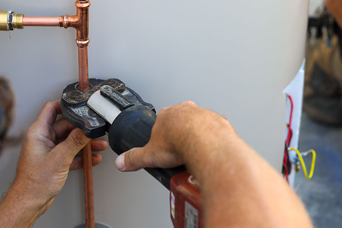 Plumber compressing copper pipes on a hot water system in Noosa